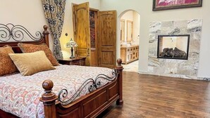 Een slaapkamer met een houten bed, een nachtkastje, een lamp en een stenen openhaard.