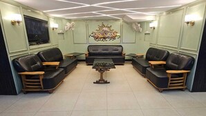 Una sala de estar con un sofá central, dos sillones, una mesa de centro y un televisor montado en la pared.
