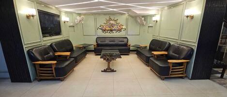 Una sala de estar con un sofá central, dos sillones, una mesa de centro y un televisor montado en la pared.
