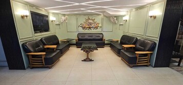 Una sala de estar con un sofá central, dos sillones, una mesa de centro y un televisor montado en la pared.