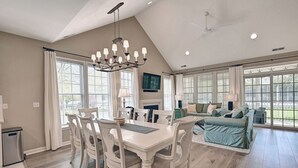 A spacious living area with a dining table, chairs, a sofa, and a fireplace. - Incredible 4BD Bear Trap Dunes Vacation Retreat! End Unit Townhome with Community Pool, Free WIFI, Golf, Beach Shuttle, Tennis, Pickleball and more! (Ocean View)