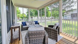 A covered porch with wicker furniture, a ceiling fan, and a view of a residential neighborhood. - Incredible 4BD Bear Trap Dunes Vacation Retreat! End Unit Townhome with Community Pool, Free WIFI, Golf, Beach Shuttle, Tennis, Pickleball and more! (Ocean View)