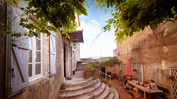 A narrow stone staircase leading to a patio area with outdoor seating and potted plants.