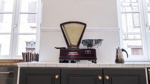 A kitchen with dark cabinets, a wall-mounted clock, and a coffee maker on the counter.