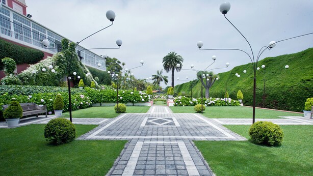 A well-maintained garden pathway leading to a building entrance, surrounded by neatly trimmed hedges and small trees. - Suites de Franchy (La Orotava)