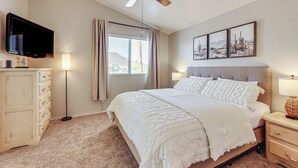 A bedroom with a bed, a ceiling fan, a TV, a nightstand, a lamp, and artwork on the wall. - Swim w/ a View: Scenic Desert Retreat in Glendale (Glendale)
