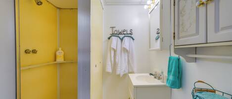 A bathroom with a yellow wall, a white sink, and a shower area.