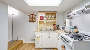 Une cuisine de taille réduite avec des meubles blancs, une cuisinière et un four à micro-ondes.