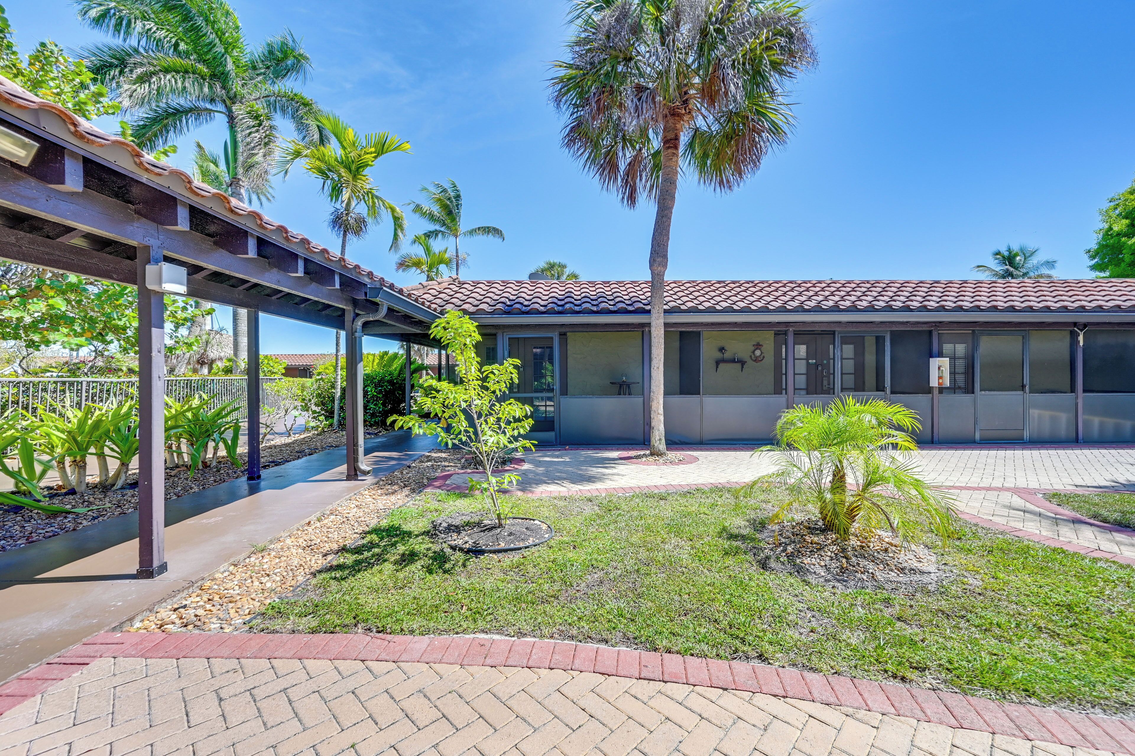 A building with a tiled roof, a covered walkway, and palm trees.