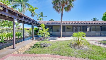 A building with a tiled roof, a covered walkway, and palm trees.