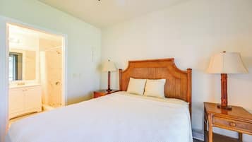 A hotel room with a large bed, wooden headboard, two bedside tables with lamps, a wardrobe, and a ceiling fan.