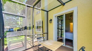 Ein durch Glas geschützter Balkon mit Tisch und Stühlen, eine Tür zum Schlafzimmer und ein Blick ins Freie.