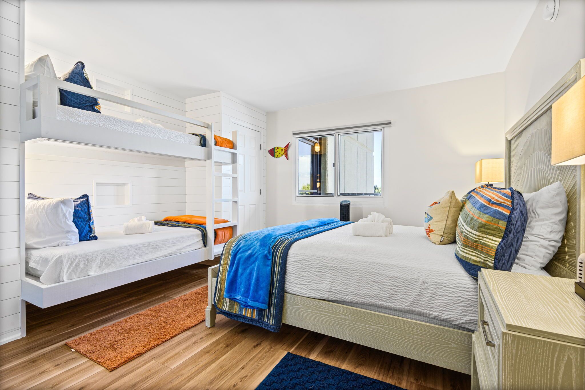 A room with bunk beds, a large bed, a mirror, and a window.
