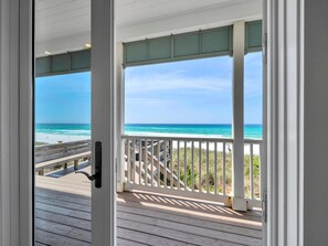 A wooden deck with a view of the beach and ocean.