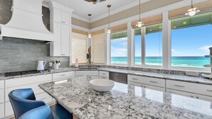 A kitchen with a large island, white cabinets, and a view of the ocean. - 4BR Beachfront Home w/ Hot tub & Private neighborhood beach access! (Santa Rosa Beach)