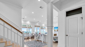 A spacious living area with a staircase, a dining area, and a view of the ocean. - 4BR Beachfront Home w/ Hot tub & Private neighborhood beach access! (Santa Rosa Beach)