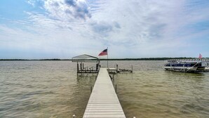 Une jetée en bois s’étendant dans une étendue d’eau calme, avec un abri couvert et un drapeau américain au bout.