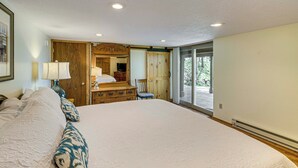 Une chambre spacieuse avec un grand lit, une commode en bois et une porte-fenêtre coulissante donnant sur un balcon.