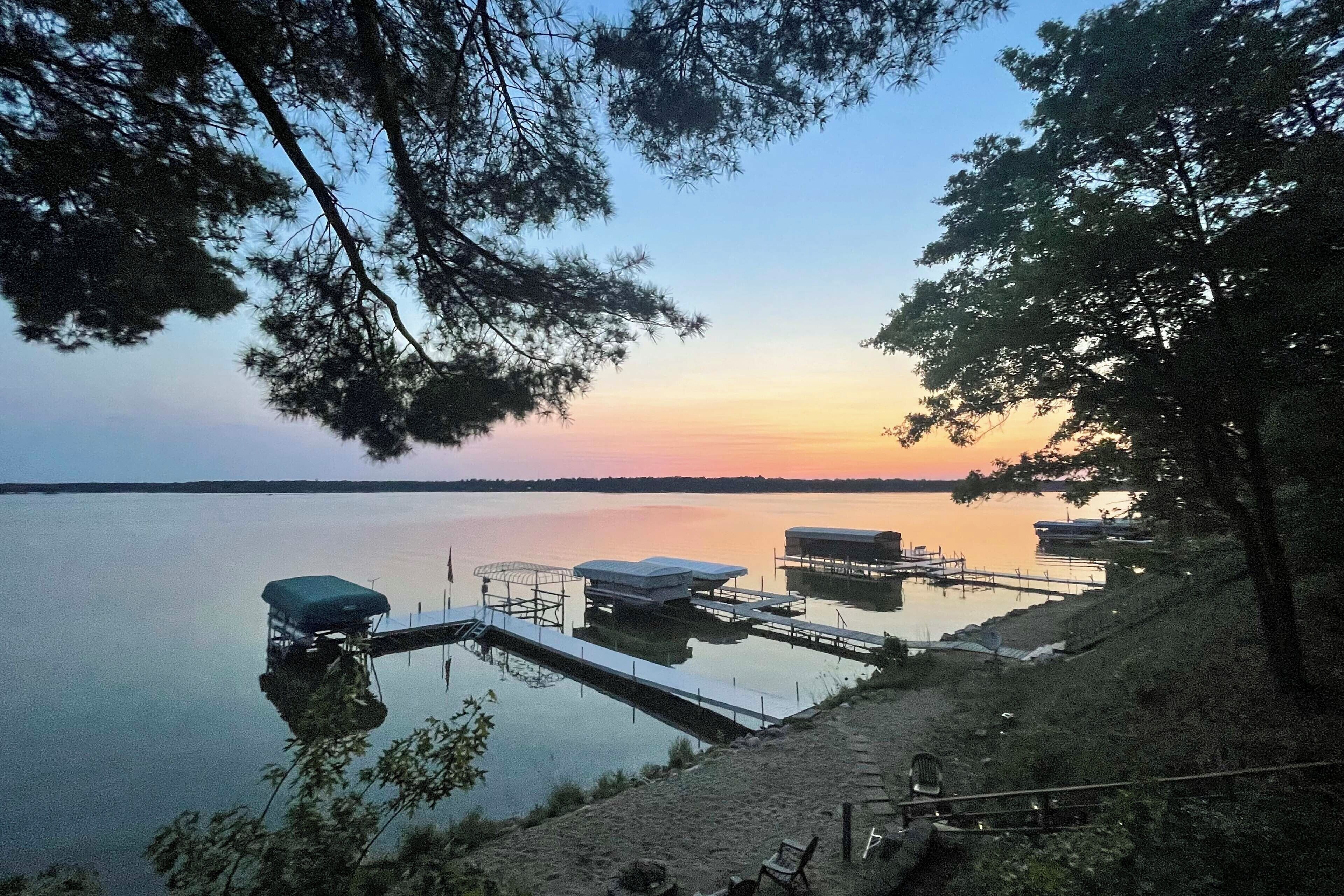 A lakeside dock with covered structures and a calm water body reflecting the sky.