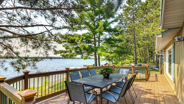 Une terrasse en bois avec une table et des chaises, donnant sur un lac.