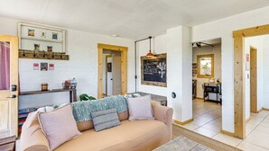 A cozy living room with a sofa, a wooden coffee table, and a kitchen area visible through an open doorway. - 5 Mi to Joshua Tree National Park: Desert Oasis! (Twentynine Palms)