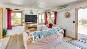 A cozy room with a bed, a TV, a wooden cabinet, and a window with curtains. - 5 Mi to Joshua Tree National Park: Desert Oasis! (Twentynine Palms)