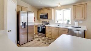 A modern kitchen with stainless steel appliances, wooden cabinets, and a large window providing natural light. - 6 Mi to Downtown Pahrump: Scenic Desert Retreat (Pahrump)