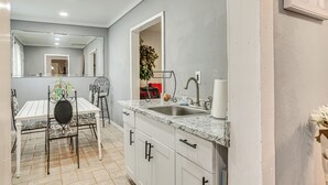 Una cocina moderna con armarios blancos, encimera de mármol y un lavamanos.