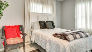 Un dormitorio con una cama, una silla y una ventana.