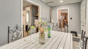 Un comedor con una mesa blanca, sillas y un florero con plantas.