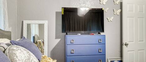 A bedroom with a bed, a dresser, a television, and a door.