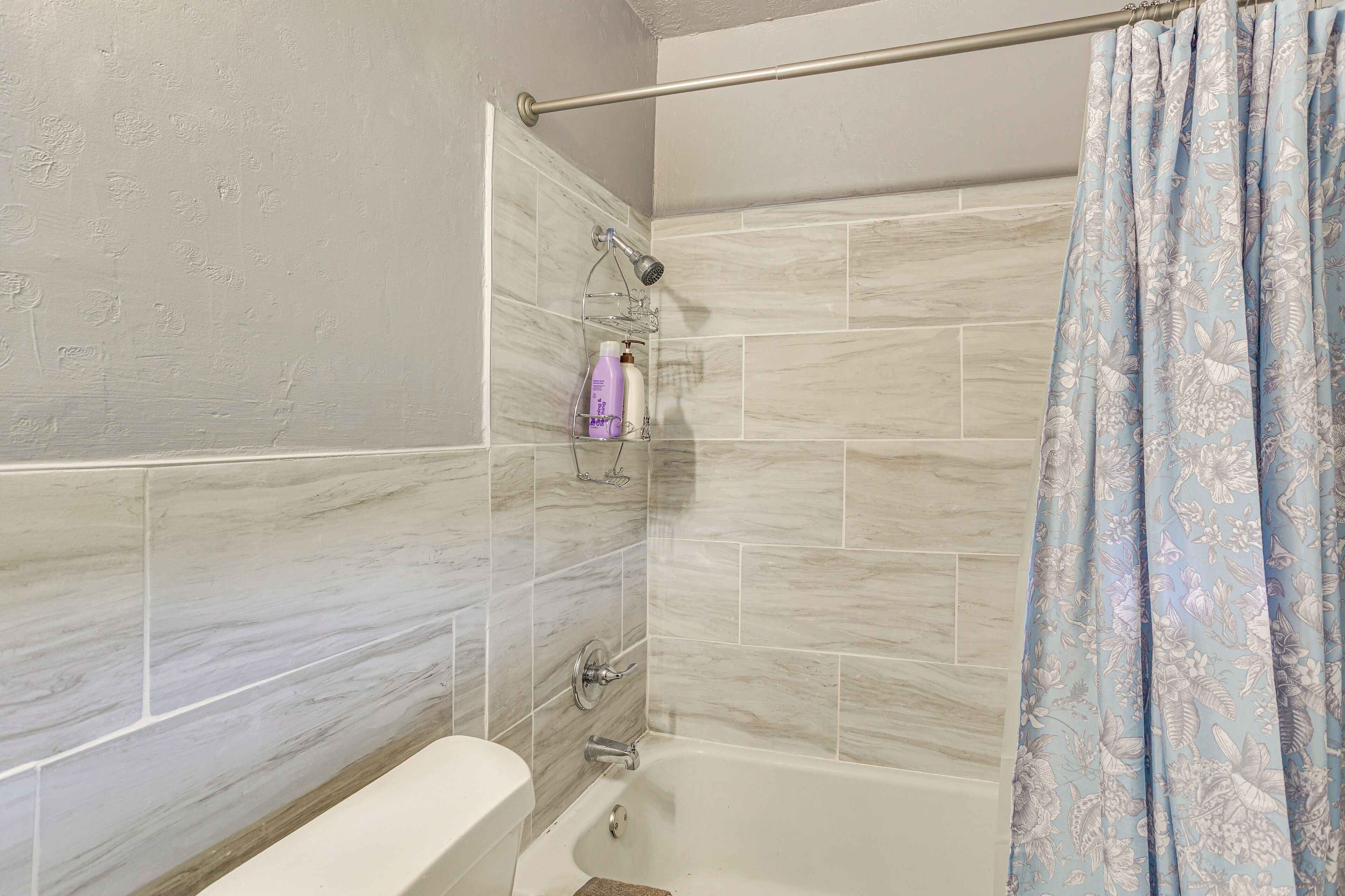 Un baño con bañera, ducha y barra de apoyo.