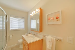 A bathroom with a sink, mirror, and window.