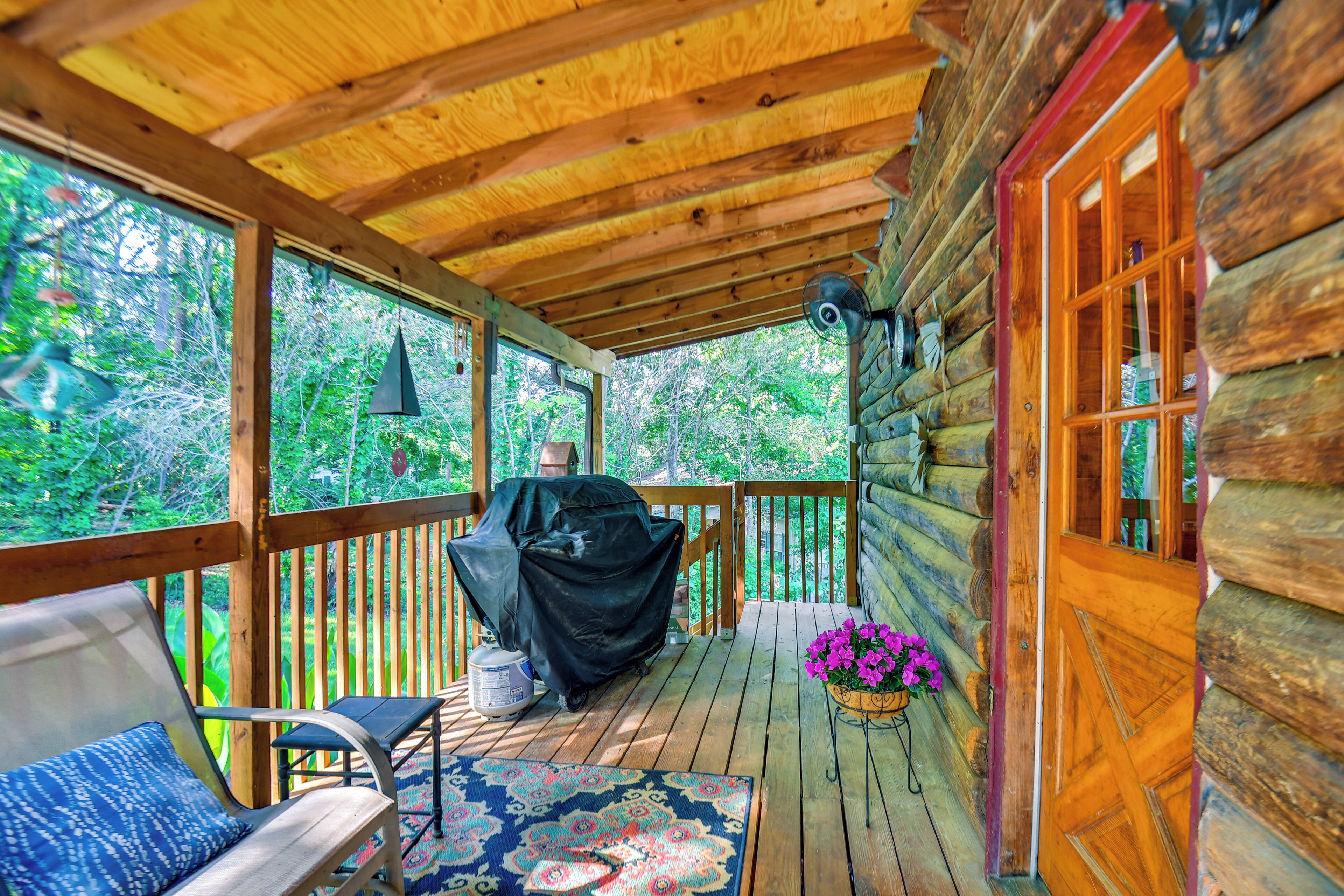Une terrasse en bois avec un barbecue couvert, une chaise, une table et un pot de fleurs.