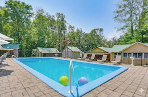 A swimming pool with lounge chairs and a fenced deck area.