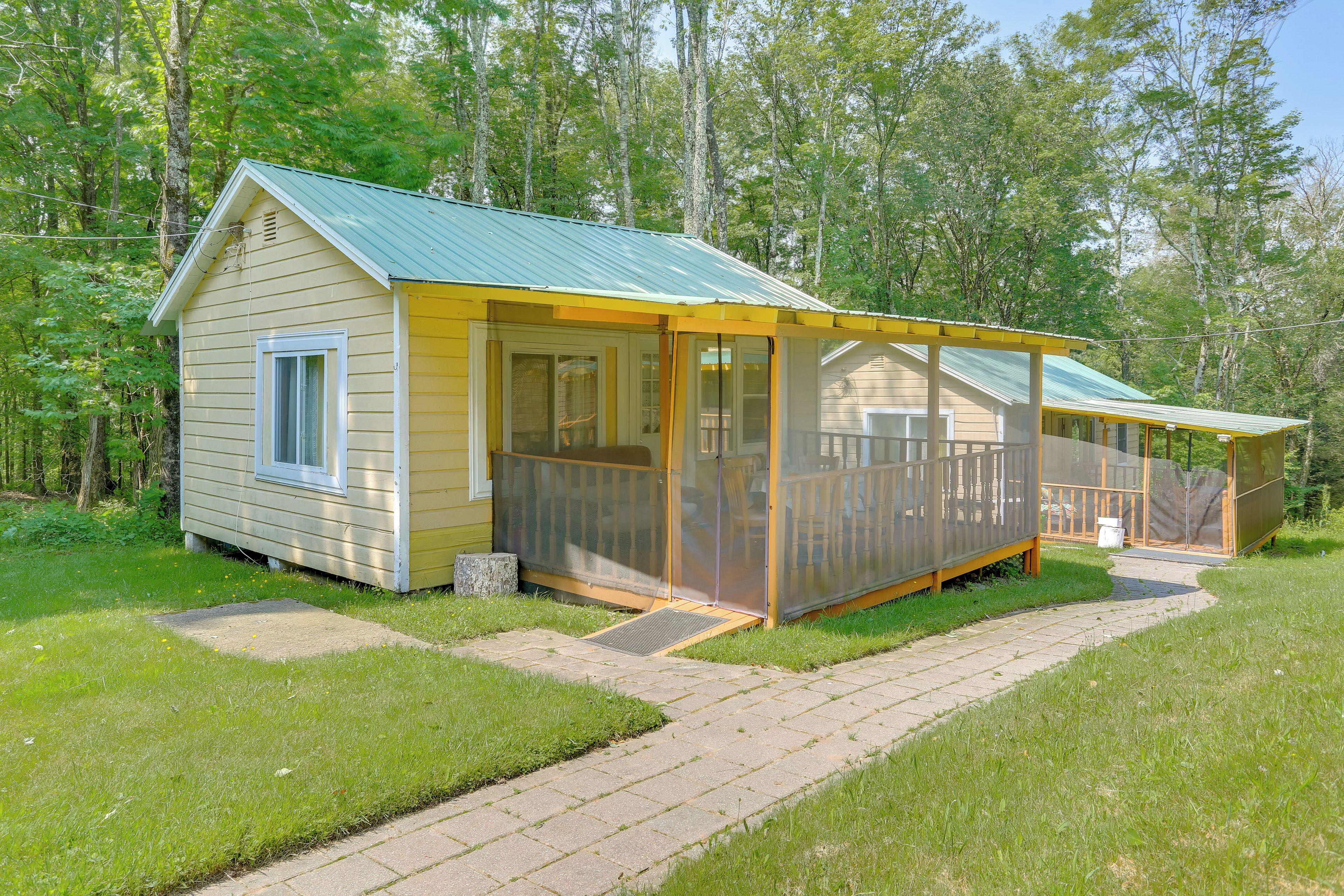 A small, single-story cabin with a covered porch and a fenced deck area.