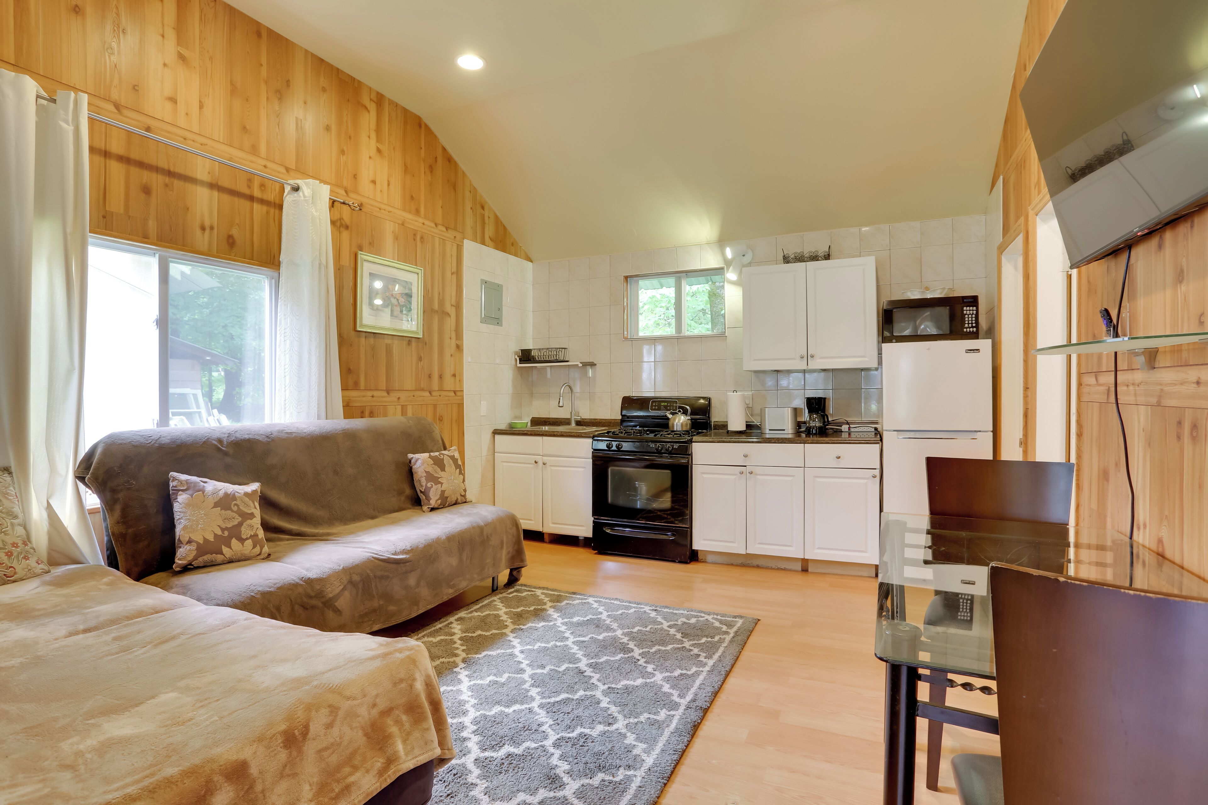A cozy living room with a sofa, a dining table, and a kitchen area with white cabinets and appliances.