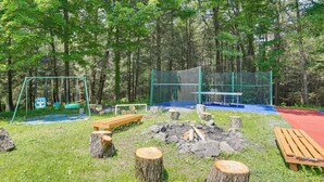 A playground with swings, a table tennis table, and a fire pit surrounded by trees. - 5 Mi to Marina & Raceways: Monticello Retreat! (Mongaup Valley)