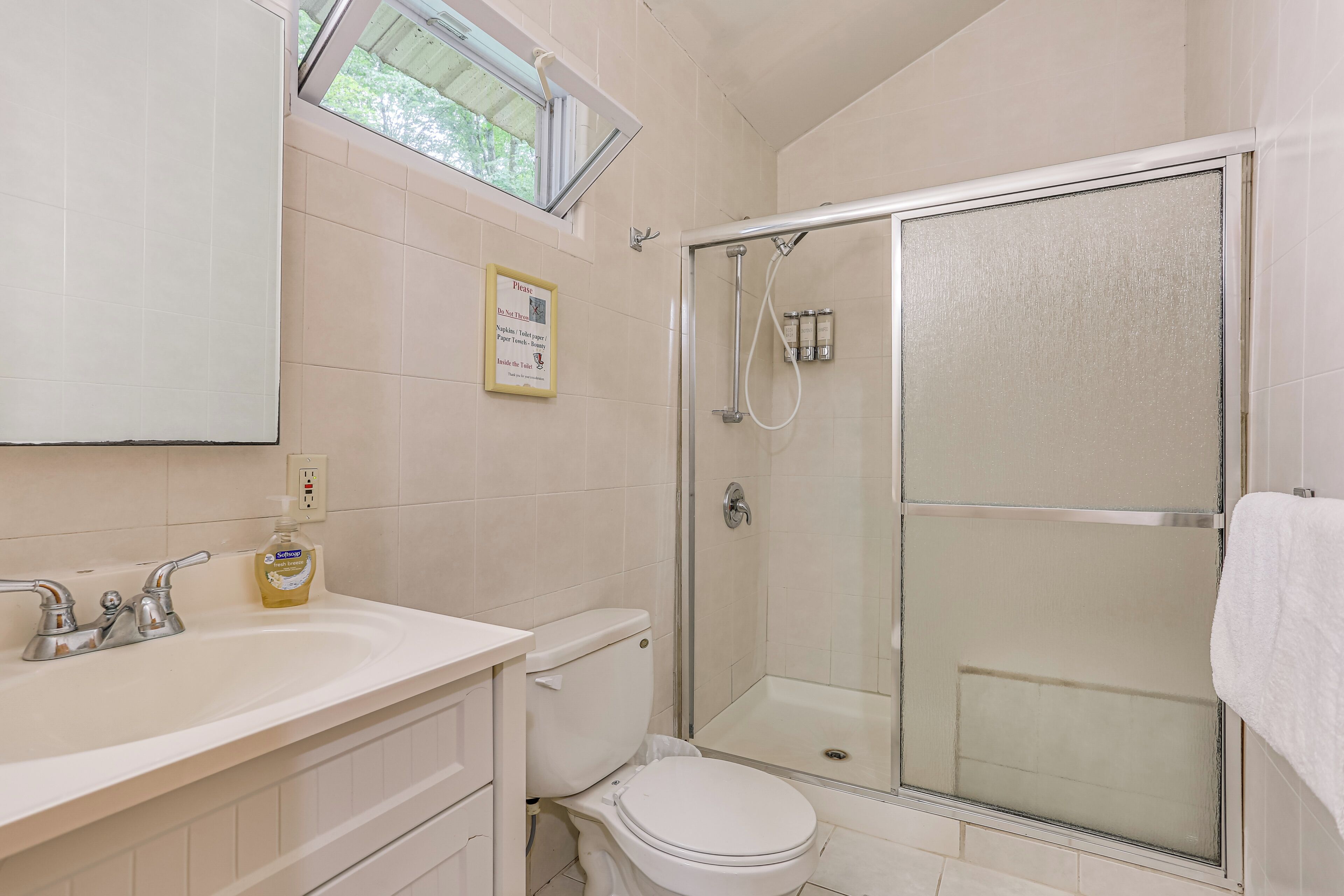A bathroom with a white sink, toilet, and glass-enclosed shower.