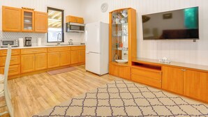 A kitchen with wooden cabinets, a microwave, a refrigerator, a clock, and a flat-screen TV mounted on the wall. - 6 Mi to State Park: Monticello Cabin! (Mongaup Valley)