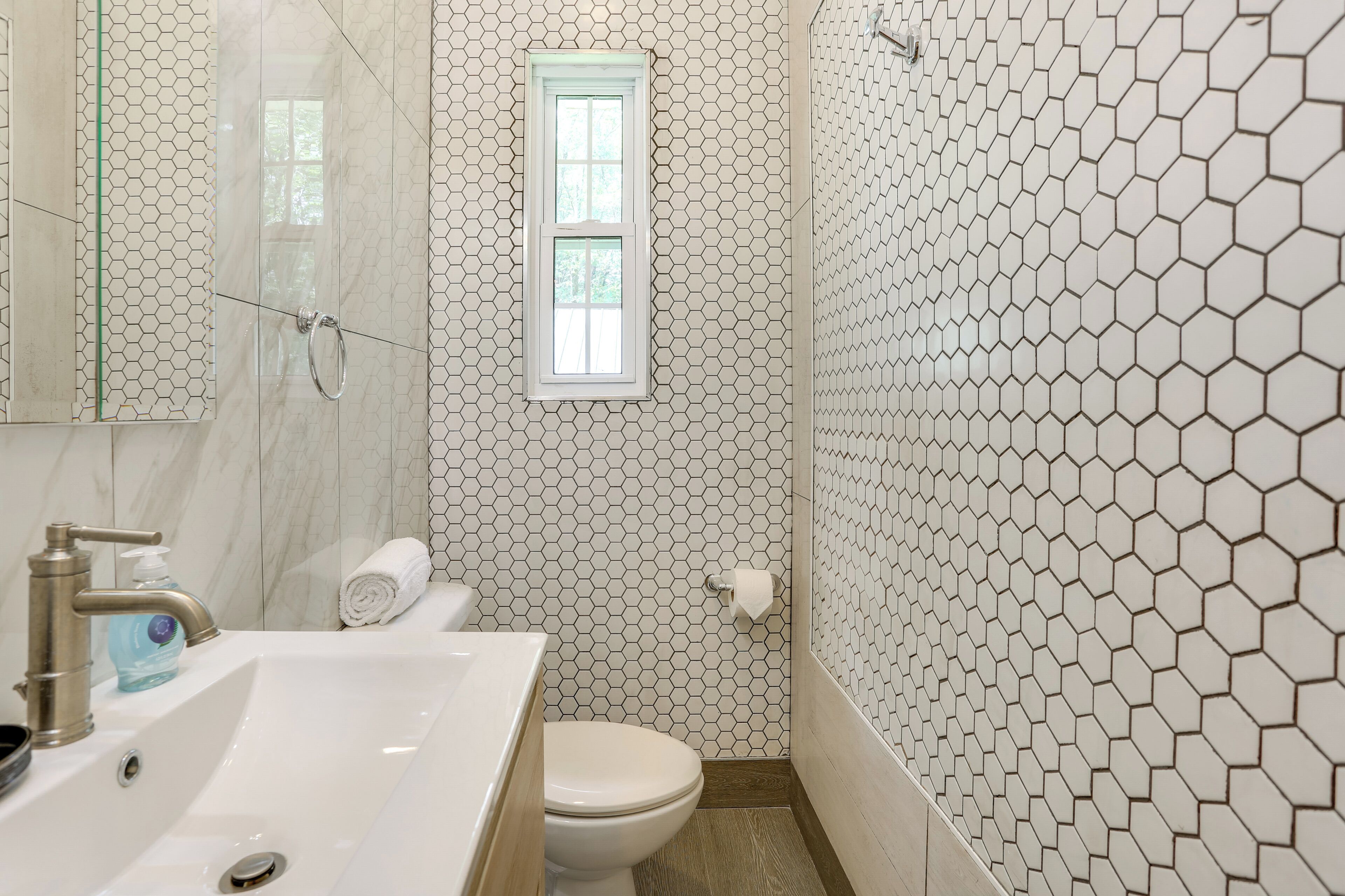 Une salle de bain avec un lavabo blanc, des toilettes et un miroir.
