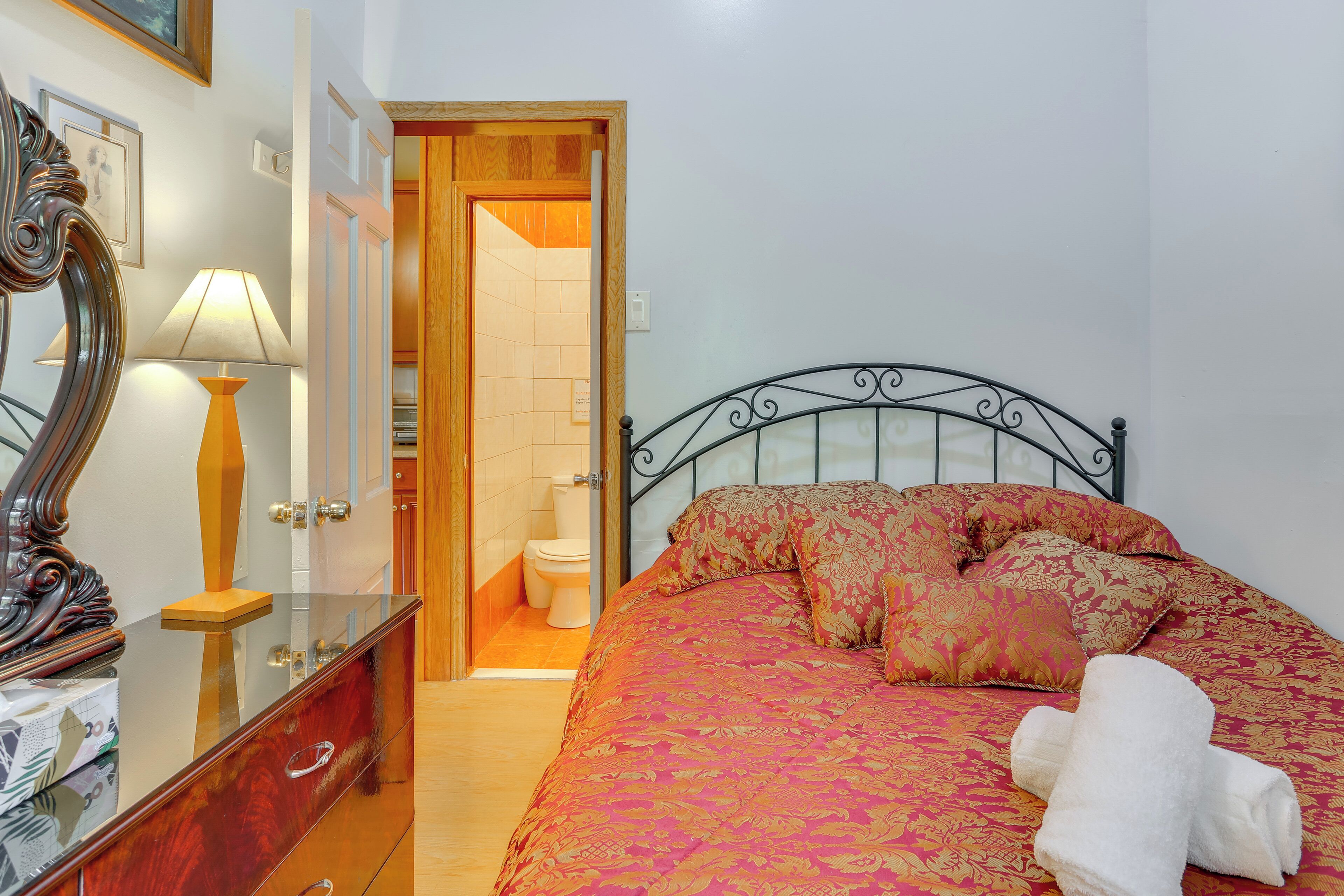 A bedroom with a bed, a wooden door, a mirror, and a lamp.
