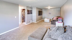 A living room with a gray couch, a white side table, and a door leading to another room. - 4 Mi to Offutt AFB - Family Home in Omaha Suburbs! (Bellevue)
