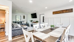 A dining area with a wooden table, white chairs, and a long white table runner. - 15 Mi to Downtown Sioux Falls: Gem w/ Yard! (Hartford)