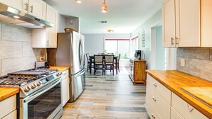 Una cocina moderna con electrodomésticos de acero inoxidable, encimeras de madera y un comedor con mesa y sillas.