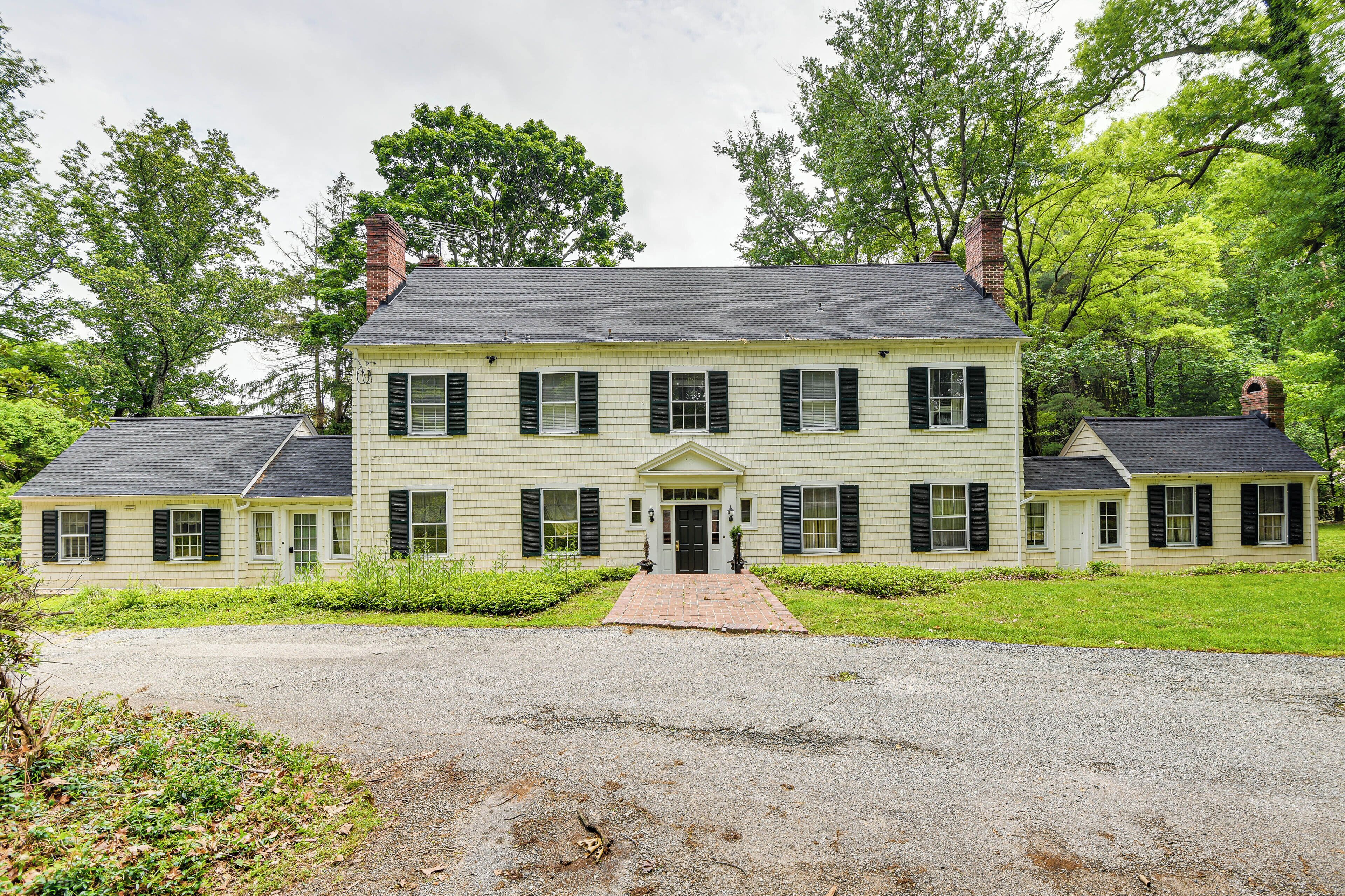 A two-story house with a central entrance, surrounded by a well-maintained lawn and trees.