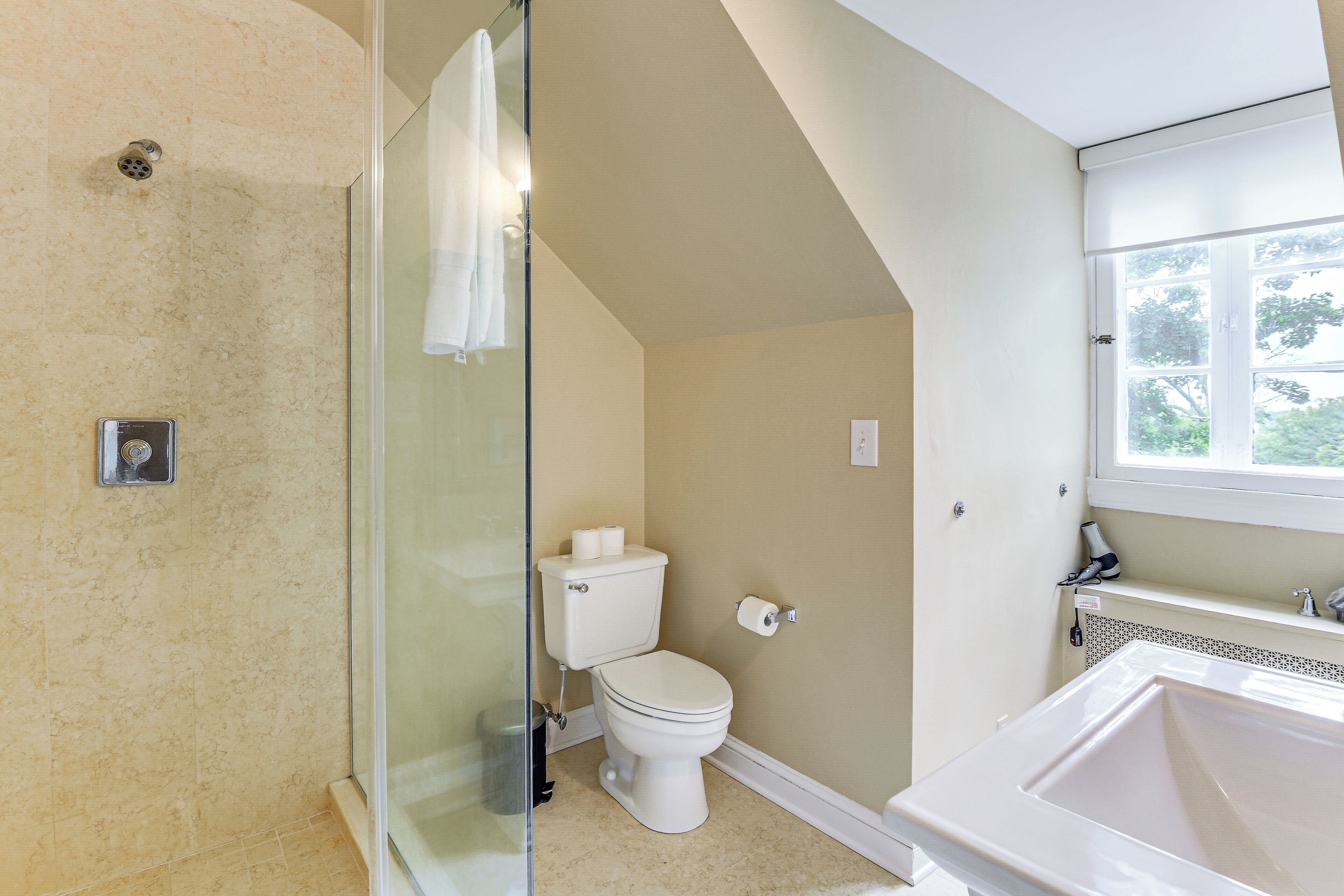 A bathroom with a glass shower enclosure, a toilet, and a sink.