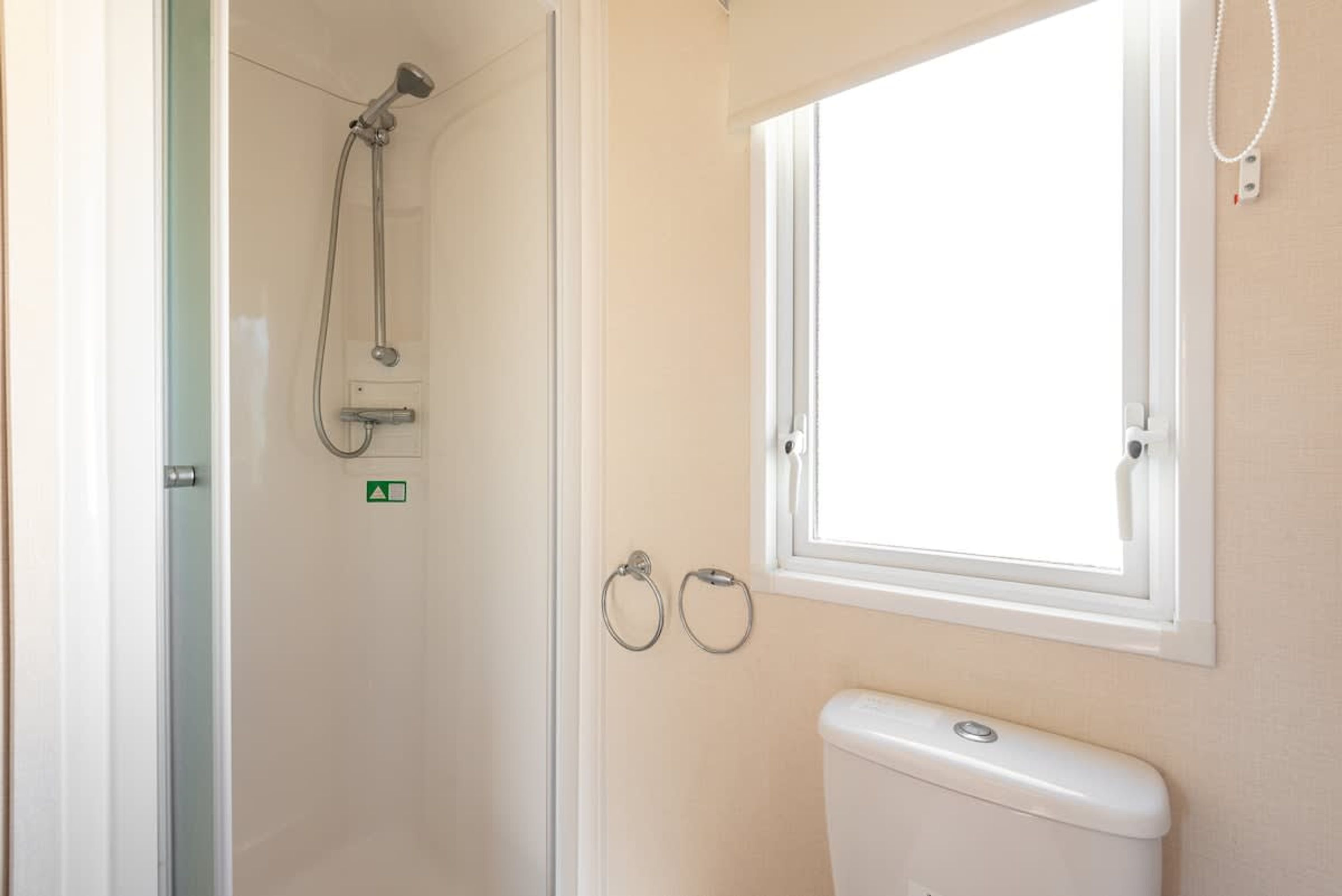 A bathroom with a shower, toilet, and window.