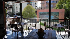 Un balcon avec une table et des chaises, une vue sur la rue et un immeuble en arrière-plan.