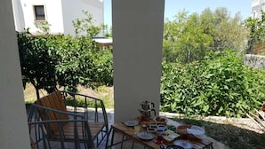 A patio area with a wooden table set for dining, surrounded by metal chairs.